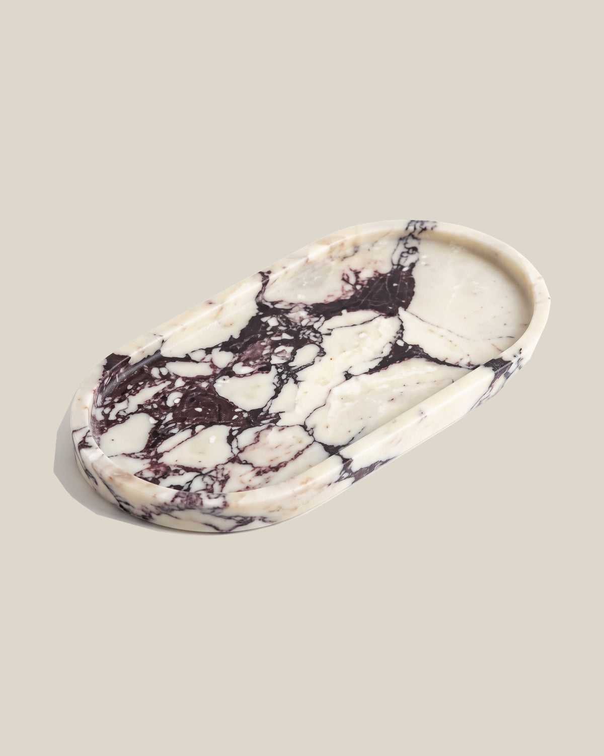 ATOMS OVAL Tray Calacatta Viola marble, angled view on a BONE background