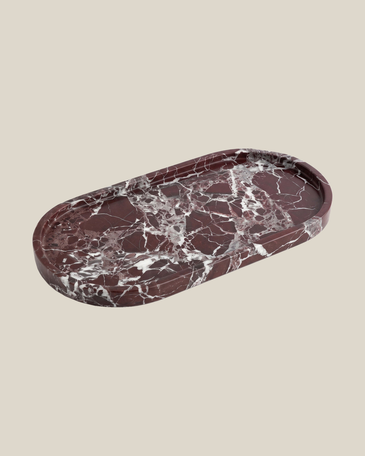 ATOMS OVAL Tray Rosso Levante marble, angled view on a BONE background