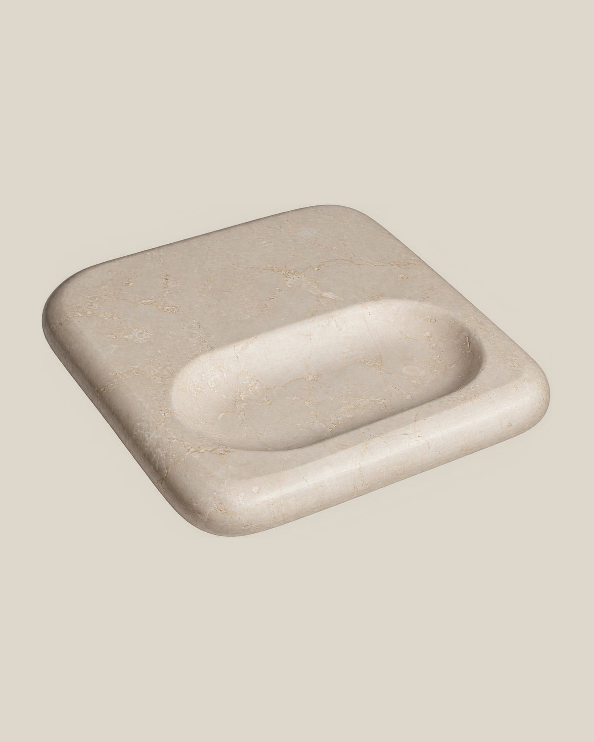 PAD Tray in beige natural stone, high-angle view showing the broad flat surface and elongated oval recess.