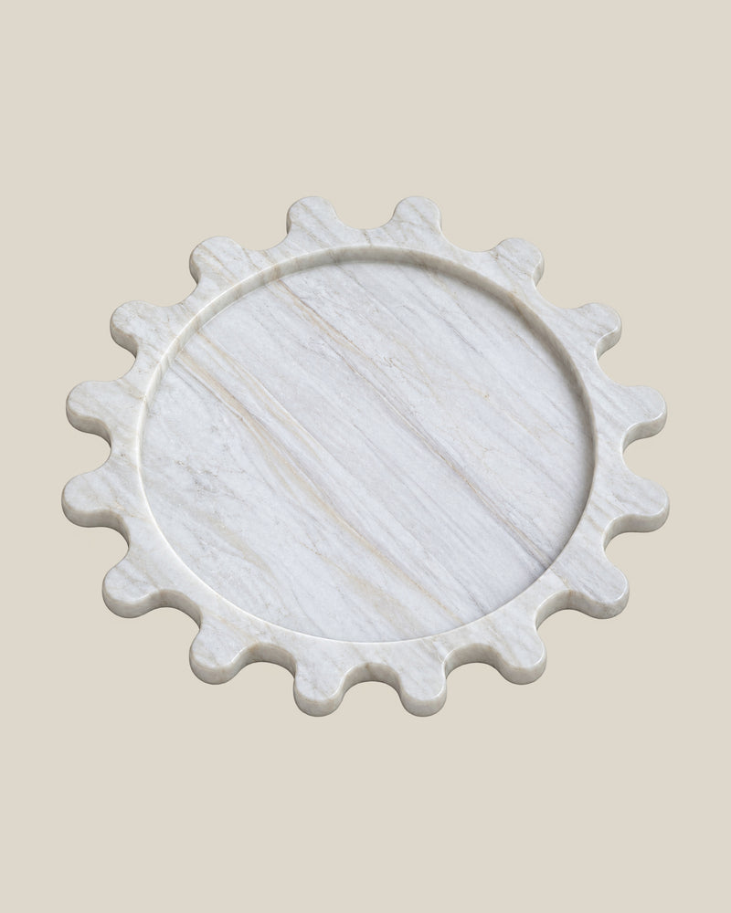Sun Orbit Tray in Calacatta Gold natural marble, three-quarter view, rounded sun rays and recessed circular centre.