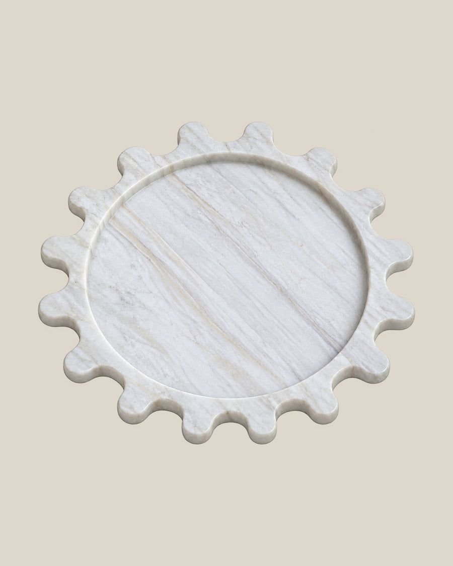 Sun Orbit Tray in Calacatta Gold natural marble, three-quarter view, rounded sun rays and recessed circular centre.